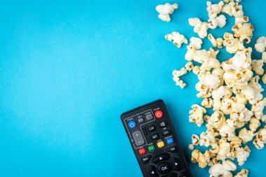 Karamelli patlamış mısır ve mavi arka planda televizyon kumandası..