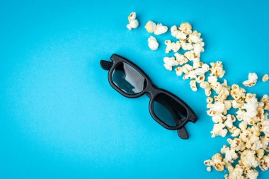 Karamelli patlamış mısır ve mavi arka planda 3D gözlük..