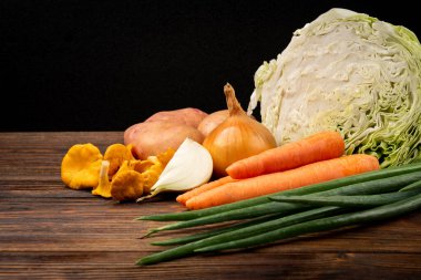 Koyu ahşap zemin üzerinde taze lahana ve havuç..