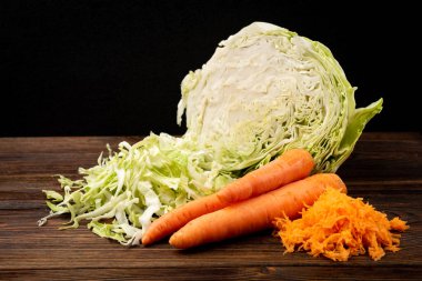 Koyu ahşap arka planda lahana ve havuç kesmek. Taze salata..