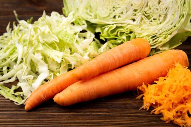 Koyu ahşap arka planda lahana ve havuç kesmek. Taze salata..