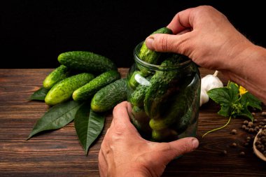 Koyu ahşap arka planda cam kavanozda taze salatalıklar..