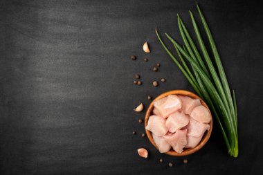 Tahta kasede çiğ fileto, sarımsak, yeşil soğan ve siyah arka planda karabiber..