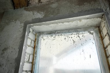 Sıvacı bir spatula ve alçı ile pencerenin köşelerini onarıyor. İnşaat bitirme işleri.