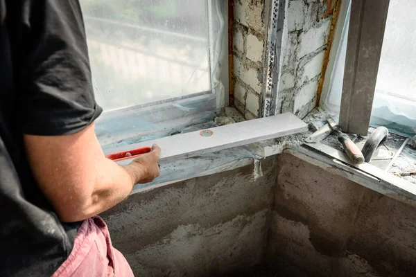 The plasterer repairs the corners of the window with a spatula and plaster. Construction finishing works.