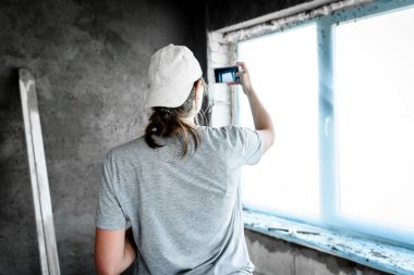 Kadın inşaat alanında fotoğraf çekmek için cep telefonu kullanıyor..