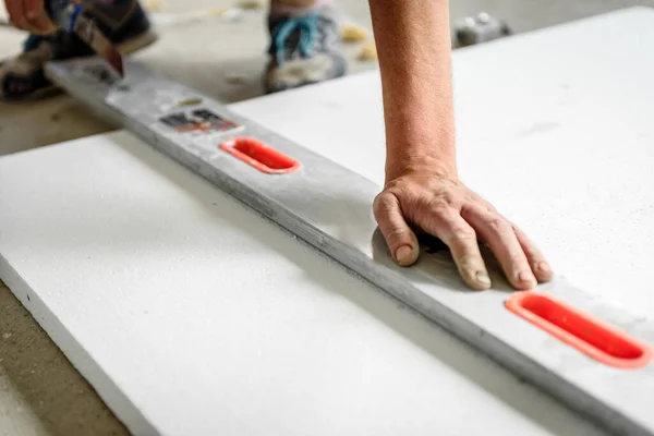 Worker mark the correct length and dimension of styrofoam on construction site.