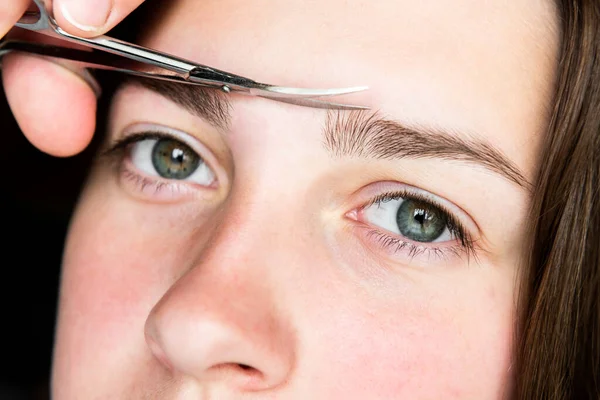 Kaşlarını makasla kesen bir kadın. Kaş düzeltmesi..