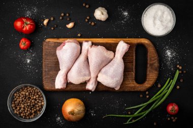 Siyah arka planda çiğ tavuk bacağı.