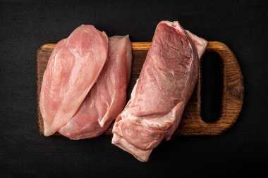 Çiğ tavuk filetosu ve siyah arka planda domuz eti..