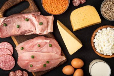 Yüksek proteinli yiyecekler - et, tavuk, süt ürünleri, tohumlar, baklagiller ve siyah arka planda yumurtalar. Sağlıklı ürünler.