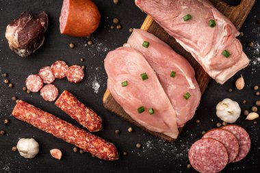 Çiğ tavuk, domuz eti ve siyah arka planda sosis..