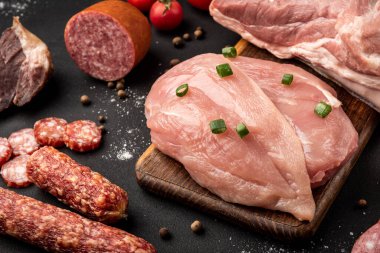 Çiğ tavuk, domuz eti ve siyah arka planda sosis..