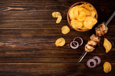 Tahta arka planda kebap ve soğanlı cips..