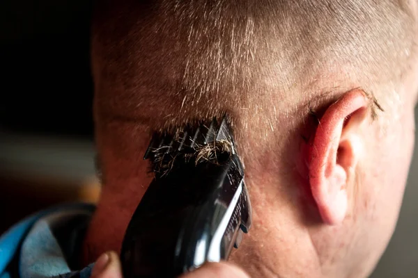 Hairdresser cuts man\'s hair with electric clipper trimmer.