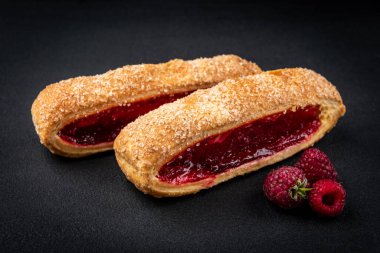 Puff pastry with cherry or raspberry jam ion black background.