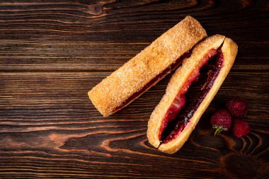 Puff pastry with cherry or raspberry jam on dark wooden background.