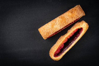 Puff pastry with cherry or raspberry jam ion black background.
