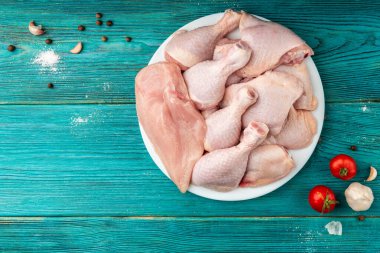 Raw chicken thighs, legs and fillet on blue wooden background.