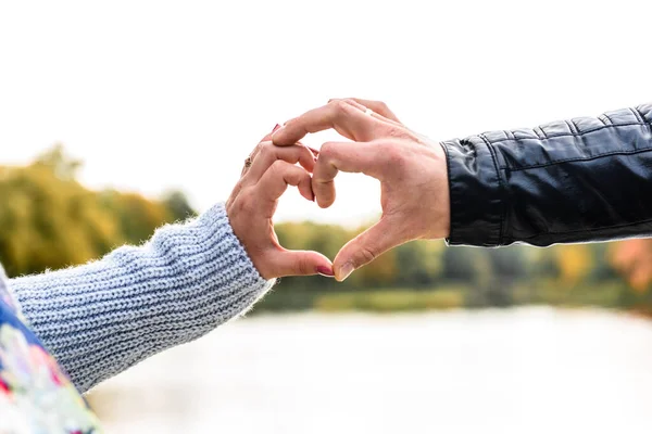 Couple in love making a heart - shape with hands