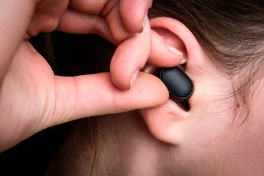 Kulağında siyah kablosuz kulaklık var..