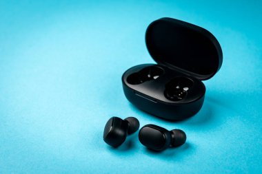 Mavi arkaplanda siyah kablosuz kulaklık.