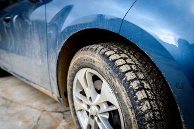 Arabanın üzerinde bataklık spreyi olan kirli bir araba tekerleği..