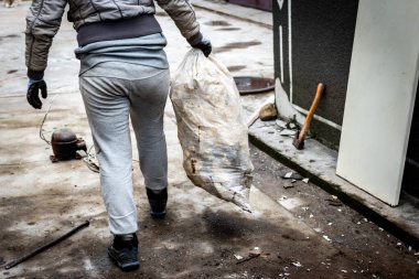 Bir kadın çöp torbasını boşaltıyor. Bahçedeki çöpleri temizliyorum..