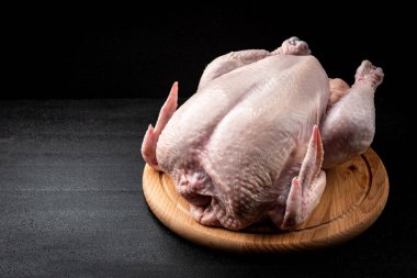Tahtada çiğ tavuk, siyah arka planda..