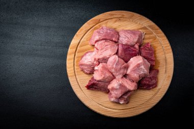 Siyah arka planda tahta üzerinde kesilmiş çiğ domuz eti..