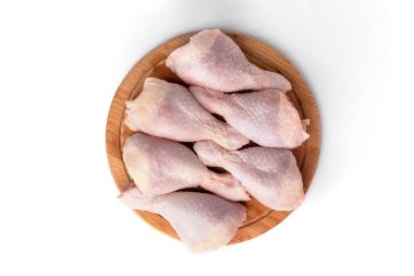 Tahtadaki çiğ tavuk bacakları beyaz arka planda izole edilmiş..