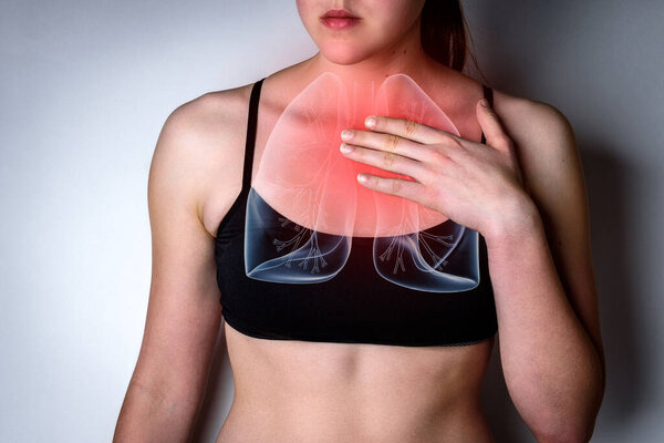 Young woman with pain in chest and lungs on gray background.