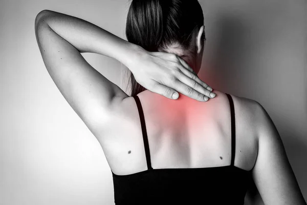 Young woman with neck pain on gray background.