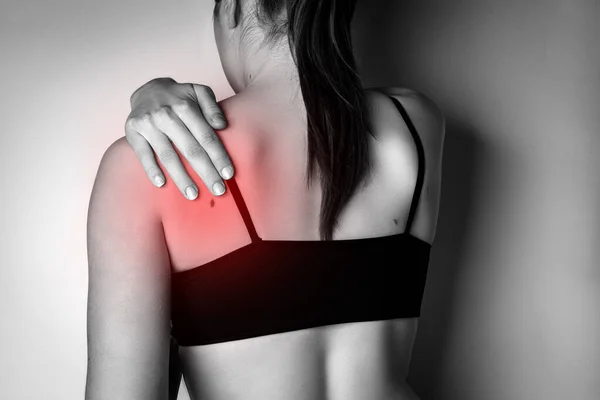 Young woman with neck pain on gray background.