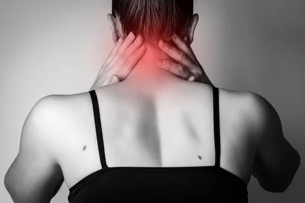 Young woman with neck pain on gray background.