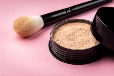 Pembe arka planda makyaj fırçası ve pudra.