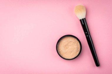 Pembe arka planda makyaj fırçası ve pudra.
