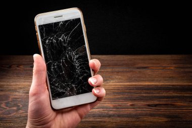 Koyu ahşap arka planda kırık cam ekran akıllı telefon..