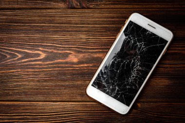 Koyu ahşap arka planda kırık cam ekran akıllı telefon..