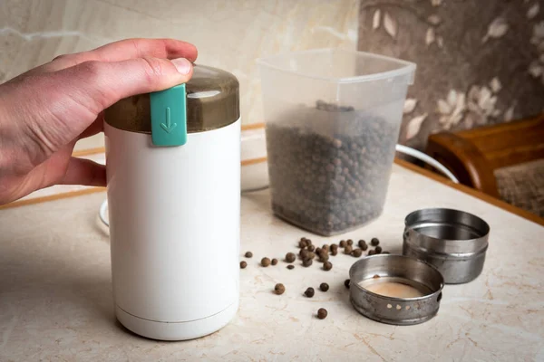 Grinding black pepper in a coffee grinder.