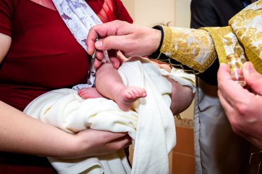 Kilisede bir çocuğun vaftiz töreni, bir rahip vaftiz ailesinin kollarında küçük bir çocuğun bacağıyla dünyayı kutsuyor..