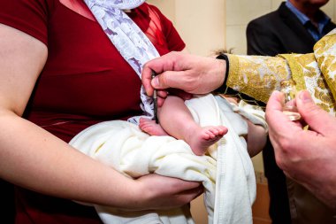 Kilisede bir çocuğun vaftiz töreni, bir rahip vaftiz ailesinin kollarında küçük bir çocuğun bacağıyla dünyayı kutsuyor..