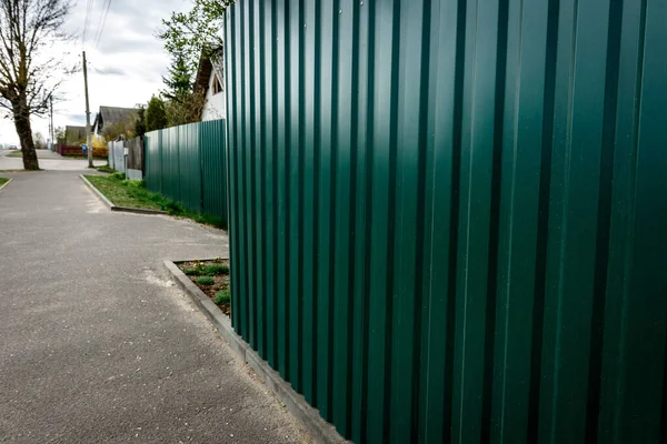 Fence of the private house with metal fence made of profiled sheet.