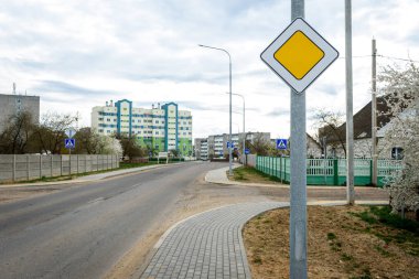 Yol ve binaların arka planında öncelikli yol tabelası.