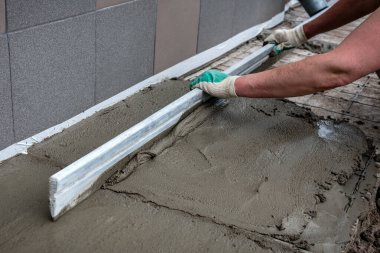 Dışarıdaki beton zemini perdeli işçiler tarıyor.