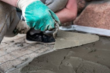 Dışarıdaki beton zemini perdeli işçiler tarıyor.