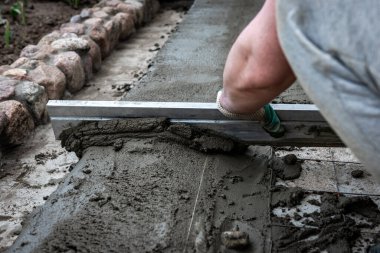 Dışarıdaki beton zemini perdeli işçiler tarıyor.