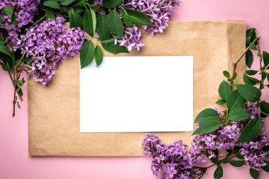 Bahar leylak dalları ve pembe arka planda beyaz boş kağıt. Bahar için kartlar, Paskalya, Anneler Günü, Kadınlar Günü, Sevgililer Günü.