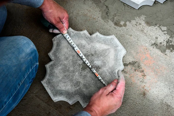 Worker hands marking concrete tile to be cut.