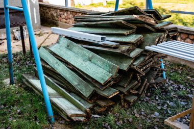 Parçalanmış çitlerin eski tahtaları ve odunları çimlerin üzerine yığılmış..